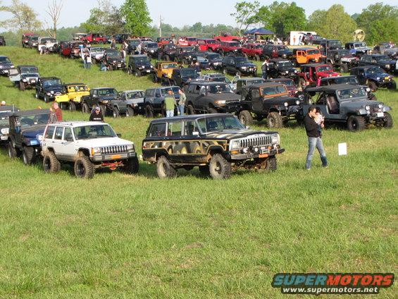 Jeep Cherokee SUV with custom paint, parked in a field with many other off-road vehicles