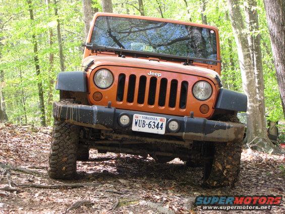 Orange Jeep Wrangler on a dirt trail in the woods. It has a Virginia license plate