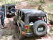 1979 Ford Bronco - Two Jeep Wranglers navigate a wet, wooded path, one with a spare tire mounted on the back.