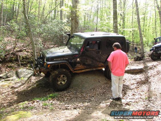 Black Jeep Wrangler Rubicon navigating an off-road trail with a person watching