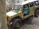 1979 Ford Bronco - A green Jeep Wrangler navigates a rocky trail with a driver inside.