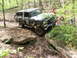 1979 Ford Bronco - This camouflaged Ford Bronco is tackling a challenging off-road course in the woods.
