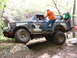 1979 Ford Bronco - A camouflaged Ford Bronco is being used for off-roading, with several people interacting with the vehicle as it traverses rough terrain.
