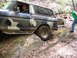 1979 Ford Bronco - A driver navigates a camouflage Ford Bronco over large rocks on a wooded trail.