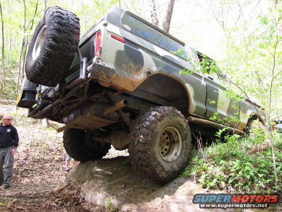 1979 Ford Bronco with camouflage paint, spare tire on rear, off-roading