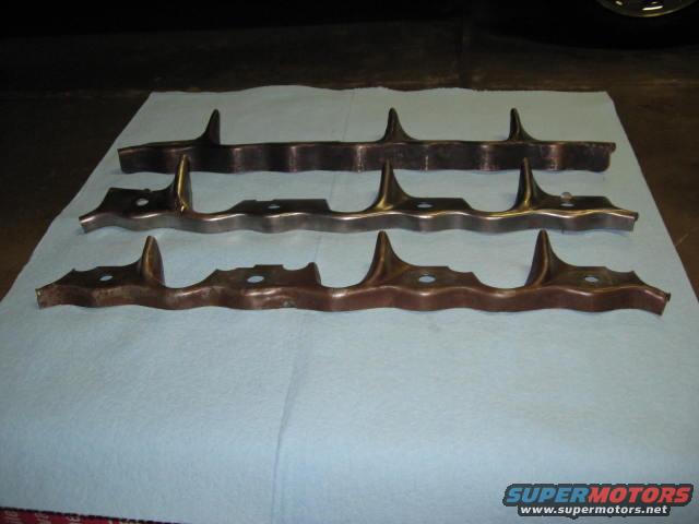 Three exhaust manifold sections laid out on a blue cloth