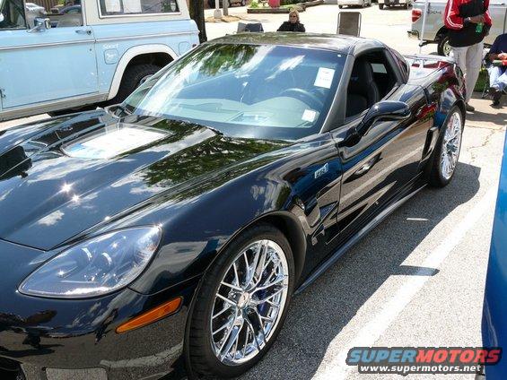 Black Chevrolet Corvette with chrome wheels parked next to a blue Ford Bronco