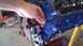 1973 Ford Torino - A hand is shown inserting a bolt into a blue engine block, likely during a repair or assembly process.
