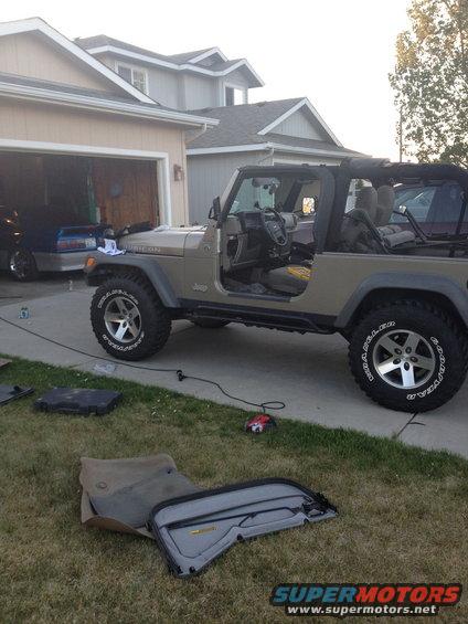 2005 Jeep Wrangler parked in driveway with doors and soft top parts on the grass