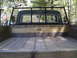 1979 Ford Bronco - The rear of a truck bed shows wooden planks and a metal cage, with an American flag in the background.