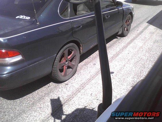 Dark sedan with custom red-accented wheels parked on asphalt