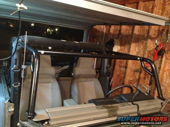 2005 Jeep Wrangler interior showing front seats, dashboard, and aftermarket roll cage installed