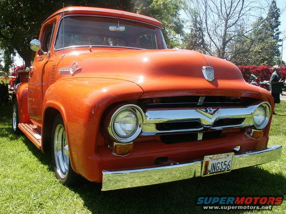 Orange 1956 Ford F-100 truck, front view, chrome grille and bumper, on grass