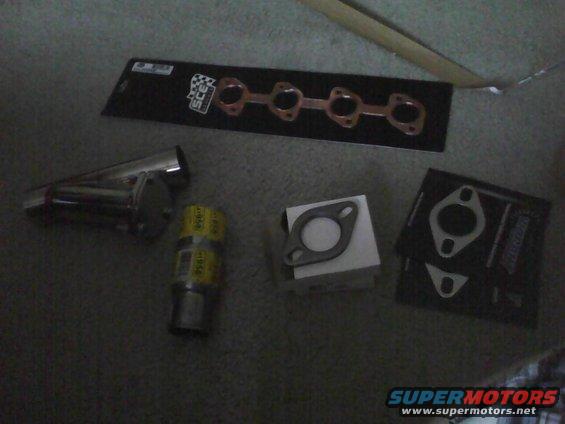 Exhaust manifold gaskets and a muffler on a carpeted surface