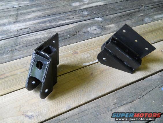 Pair of black metal suspension parts on wooden background