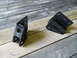 1992 Ford Bronco - Two black metal suspension components are displayed on a weathered wooden surface.