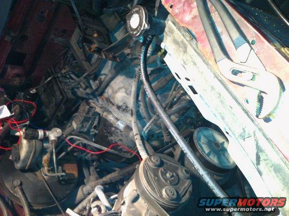 Engine bay with hoses, wires, and a pair of pliers on the fender