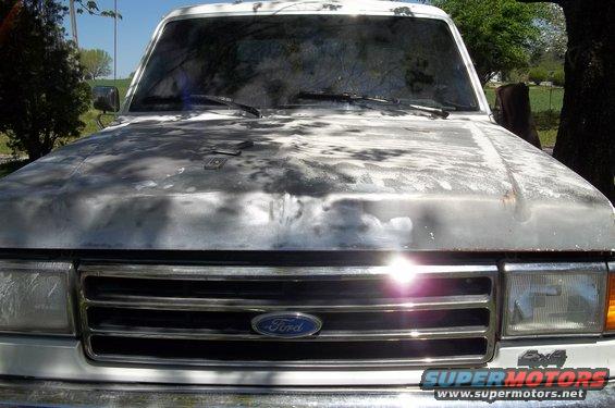 White 1990 Ford Bronco front view, hood paint faded, chrome grille, "4x4" badge visible
