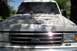 1990 Ford Bronco - The front of a white 1990 Ford Bronco shows significant paint wear on the hood and a "4x4" badge on the fender.