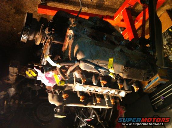 engine assembly with yellow and pink tape on hoses, on an engine stand