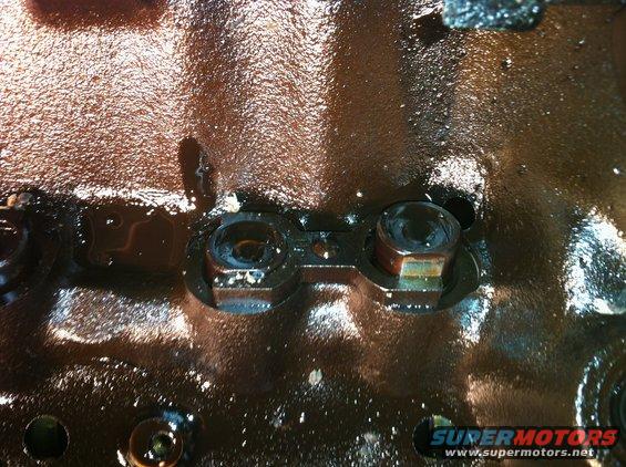 Close-up of engine components with oil and bolts