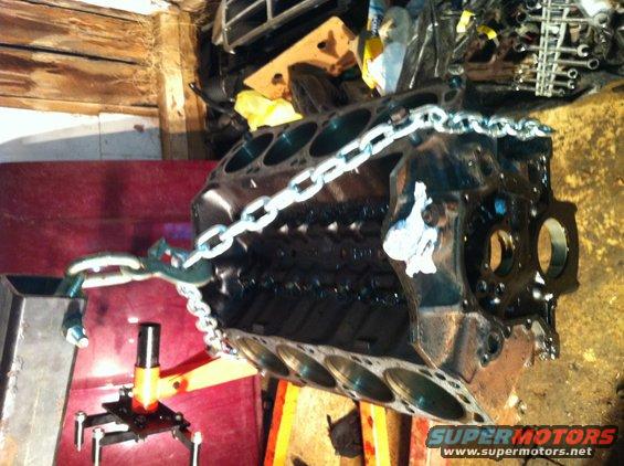 Engine block on an orange engine stand, secured with a metal chain