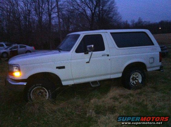 White 1992 Ford Bronco parked on grassy field at dusk