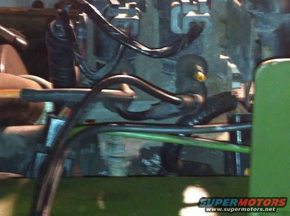 Engine bay with green painted metal, black hoses, and electrical connectors