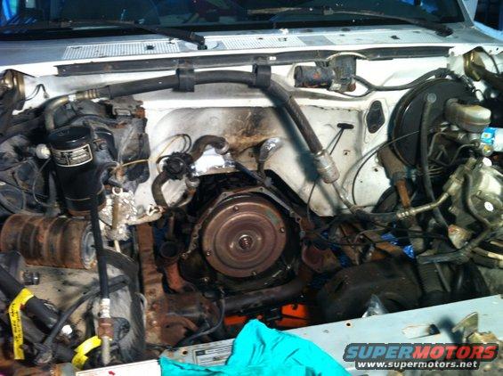 Engine bay with transmission visible, white vehicle