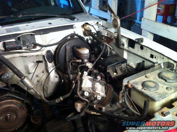 White 1992 Ford Bronco engine bay with visible air conditioning compressor and brake fluid reservoir