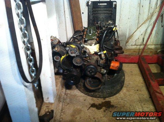 Engine assembly on a tire, with chains and a red engine hoist nearby