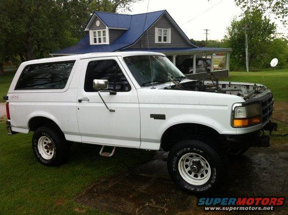 White 1992 Ford Bronco parked on grass, hood open, house in background
