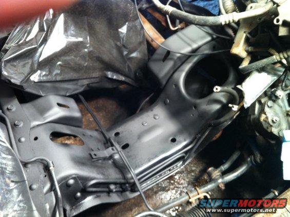 Close-up of black painted vehicle frame and engine parts, some covered with plastic