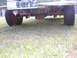 1993 Ford Bronco - The underside of a truck shows its rear axle, hitch, and tires on a grassy surface.