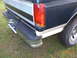 1993 Ford Bronco - Rear view of a dark green and white pickup truck, showing the bumper and taillight.