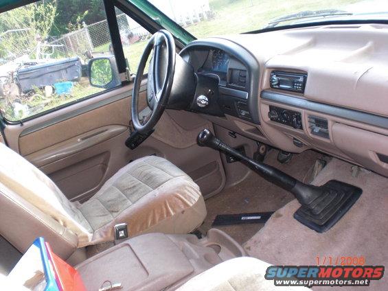 Interior of a 1990s truck, showing the dashboard, steering wheel, seats, and floor shifter