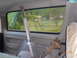 1993 Ford Bronco - The interior of a vehicle is visible, a seatbelt and a rusty pipe, with a view of a rural landscape through the window.