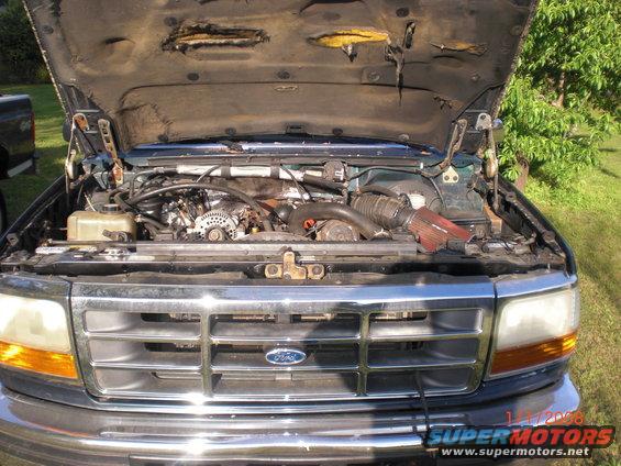 Green Ford truck engine bay with hood open, chrome grille, and aftermarket air intake