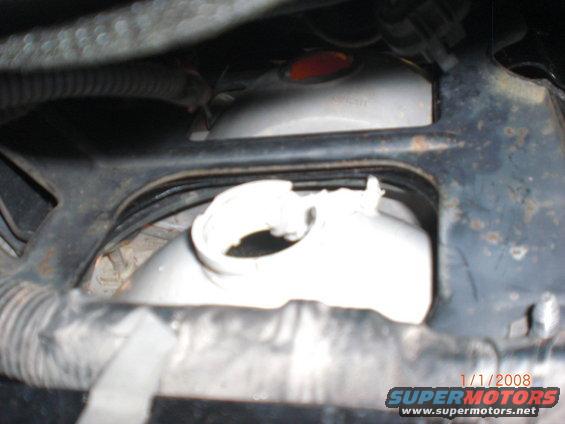 Close-up of a vehicle's coolant reservoir and surrounding metal bracketry