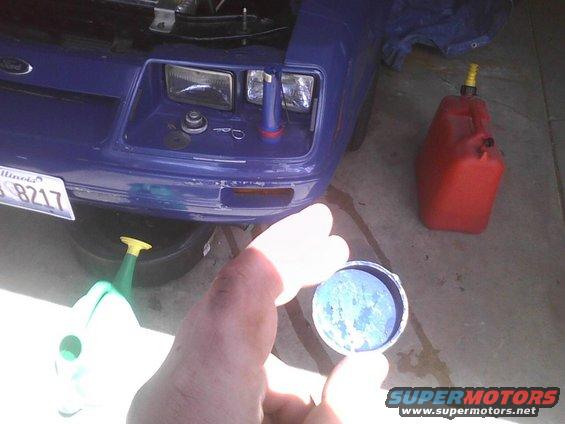 Blue car front end with oil drain pan and gas can