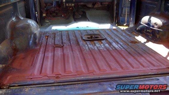 Interior of a truck bed with red primer and exposed wiring in the cabin. Looks like it's being prepped for work