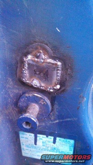 Welded metal part with bolt and sticker on blue surface