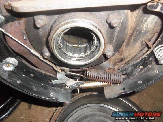 Close-up of a rear drum brake assembly with brake shoes, springs, and wheel bearing visible