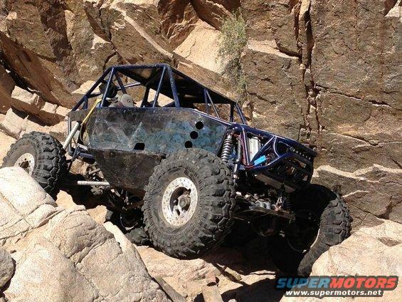 Custom off-road buggy with roll cage and large tires navigating rocky terrain