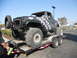1986 Ford Bronco - A heavily modified pickup truck with oversized tires is being transported on a trailer.