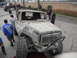 1986 Ford Bronco - A heavily modified pickup truck, covered in mud, sits in a parking lot with onlookers.