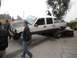 1986 Ford Bronco - A heavily modified pickup truck is parked on top of a smaller car, with onlookers observing the scene.