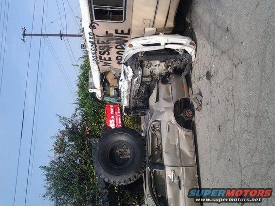 Wrecked silver sedan with a bus in the background, text on bus reads 'WESSEL PROPANE'