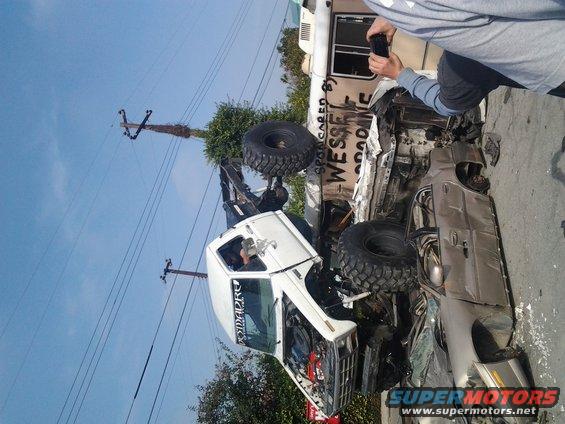 two wrecked off-road trucks, one on its side, with large tires and damage