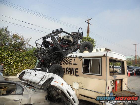 Off-road buggy atop a bus, crushing cars below